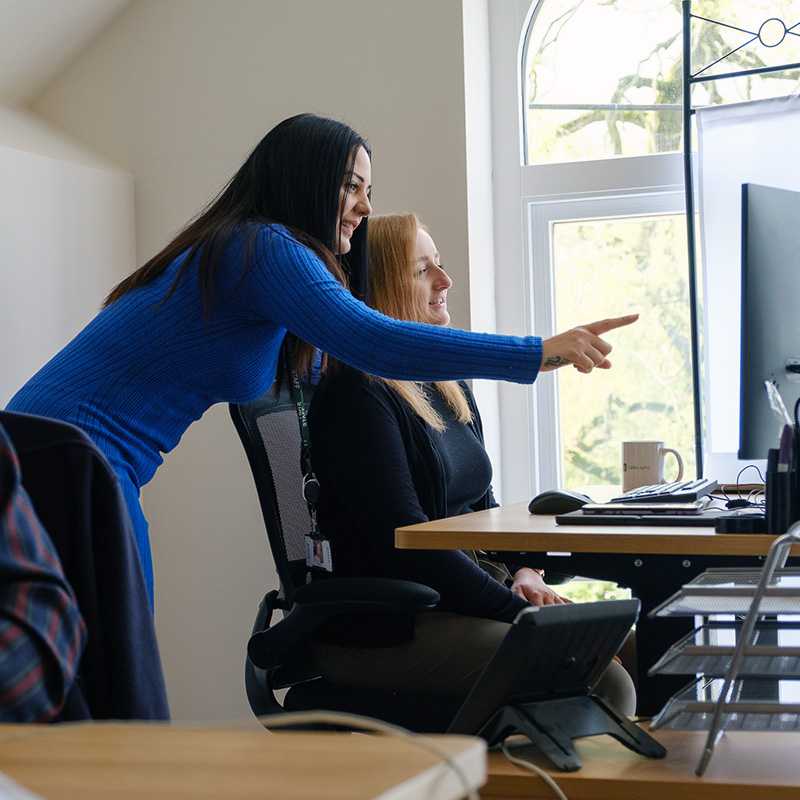 Two people at work in at a desktop computer