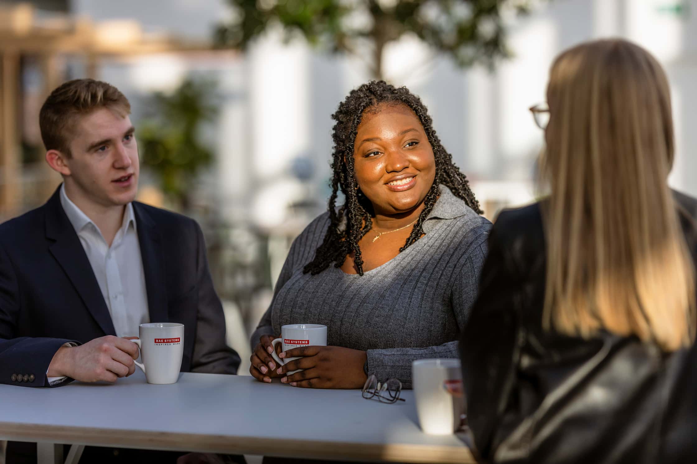 Three employees having a coffee break at an outside table