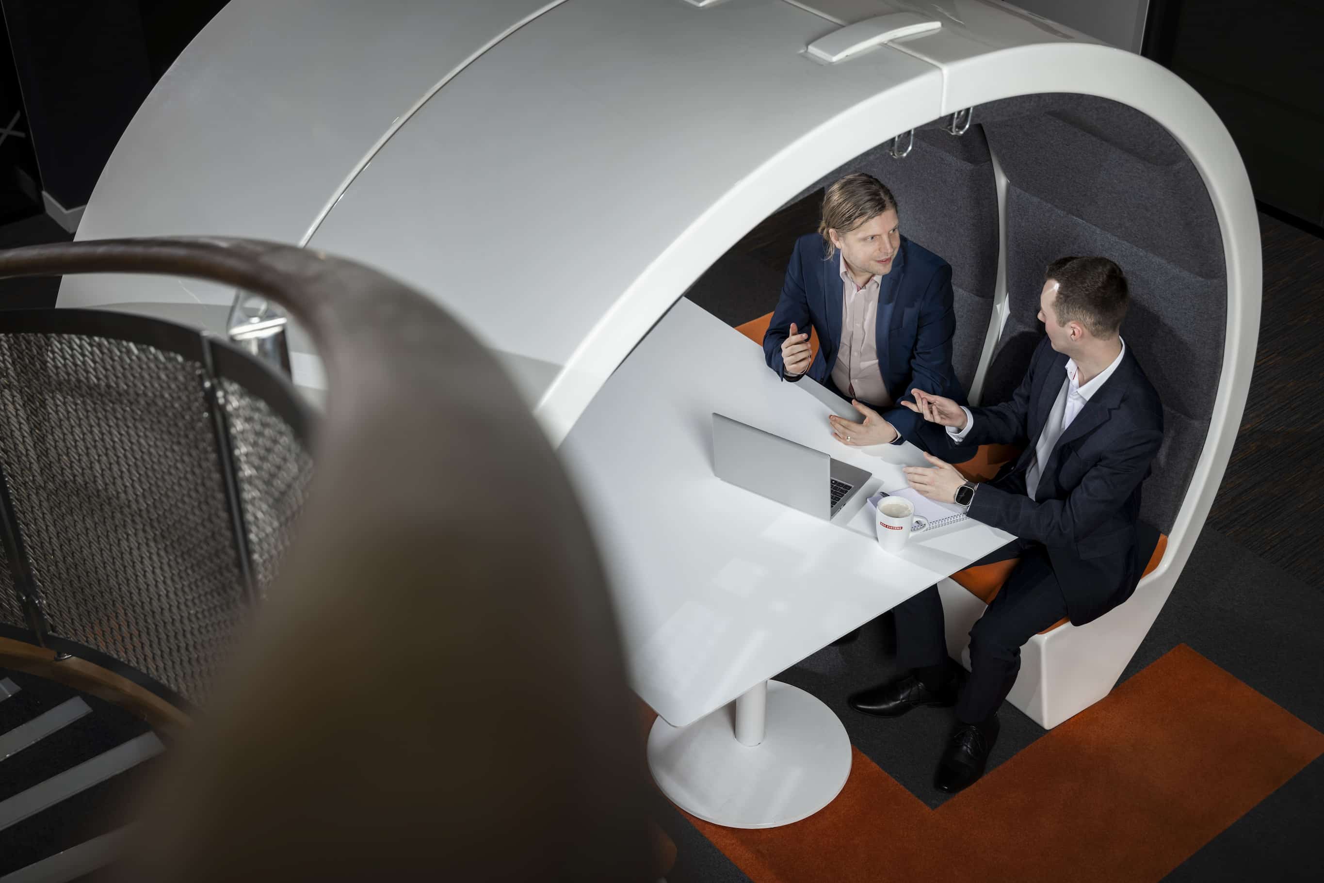 Aerial shot of two colleagues conversing in a modern office booth