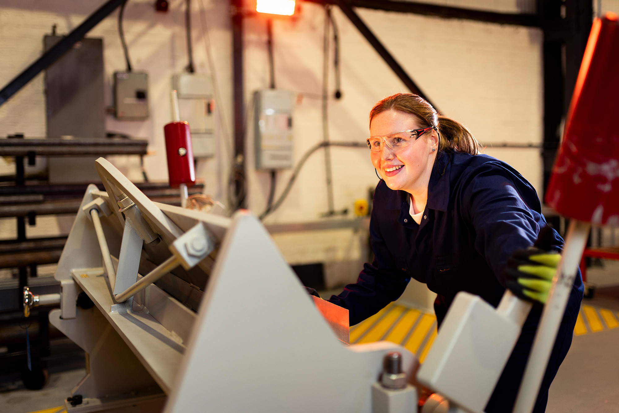 Young woman at manufacturing machinery