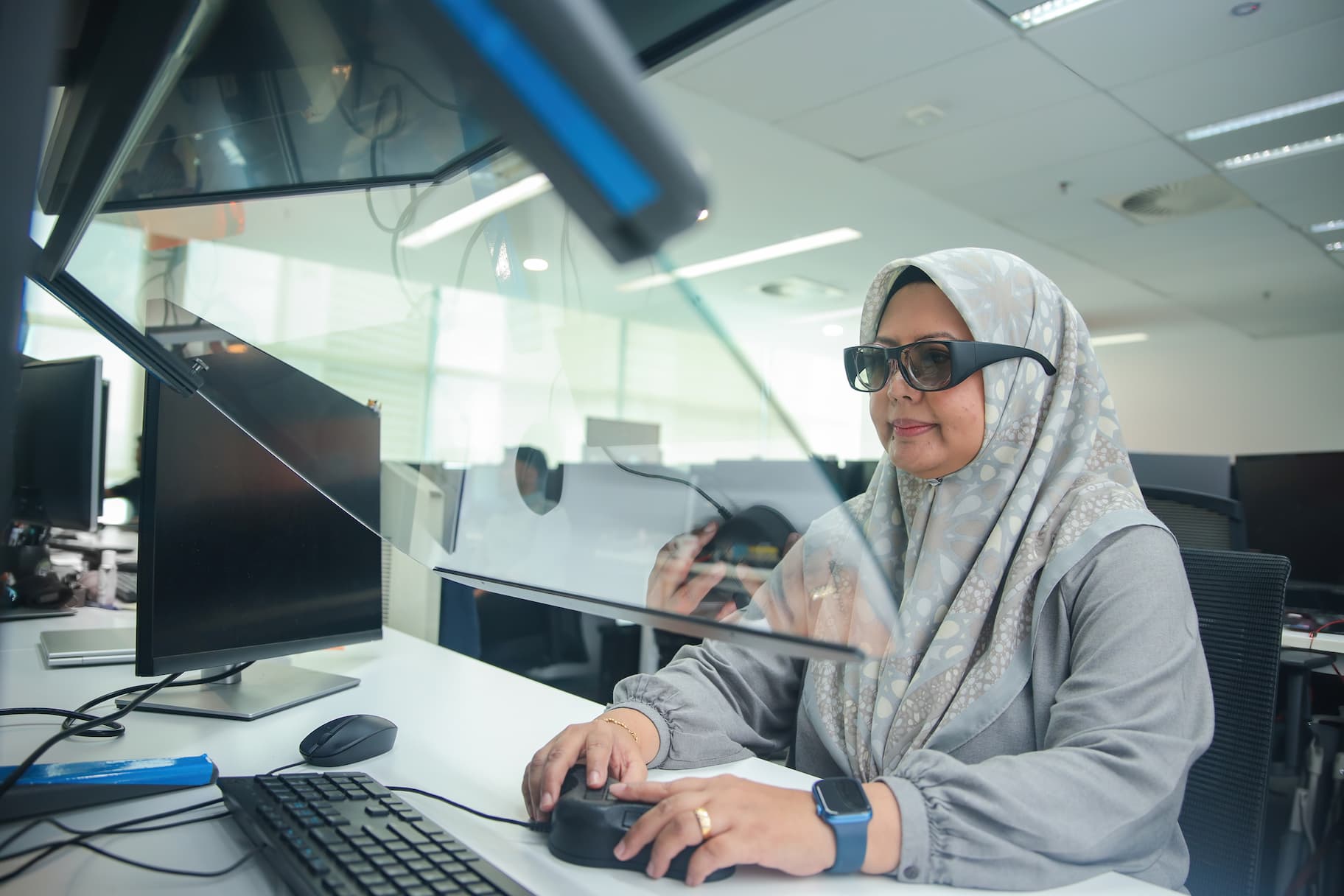 Woman in modest dress at computer wearing advanced eyewear