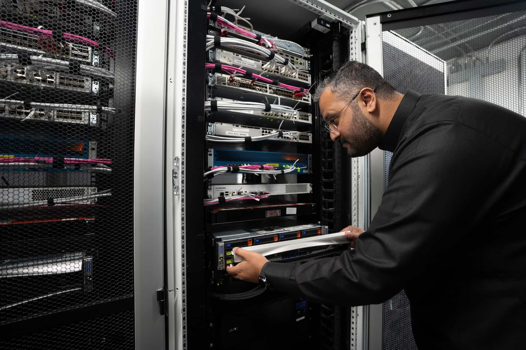 Man fitting a part into a bank of servers