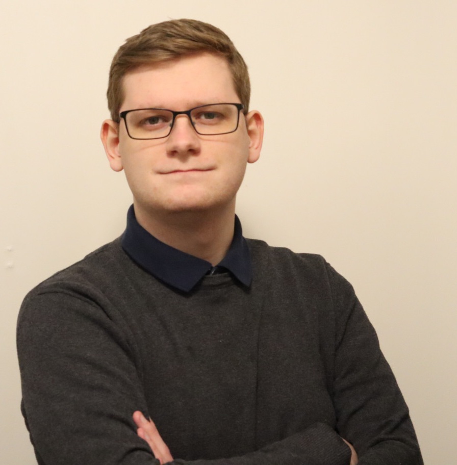 Man wearing glasses and a black top with his arms crossed